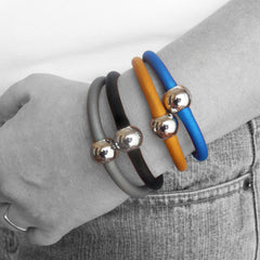 Closeup of arm with multiple TUBINO SPORTIVO linkable BRACELETS in array of fashion colors, luxurious hypoallergenic synthetic rubber with nickel-free metal links, easily cut to size, Made in Italy